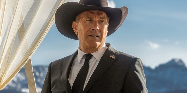 Kevin Costner portrays John Dutton in a photo from "Yellowstone" wearing a black cowboy hat, suit and tie, looking off in the distance
