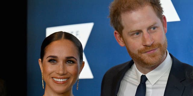 Meghan Markle and Prince Harry pose together for a photo at an event.