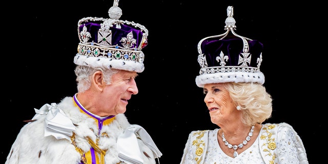 King Charles in his royal regalia looking at Camilla in a white gown wearing a crown