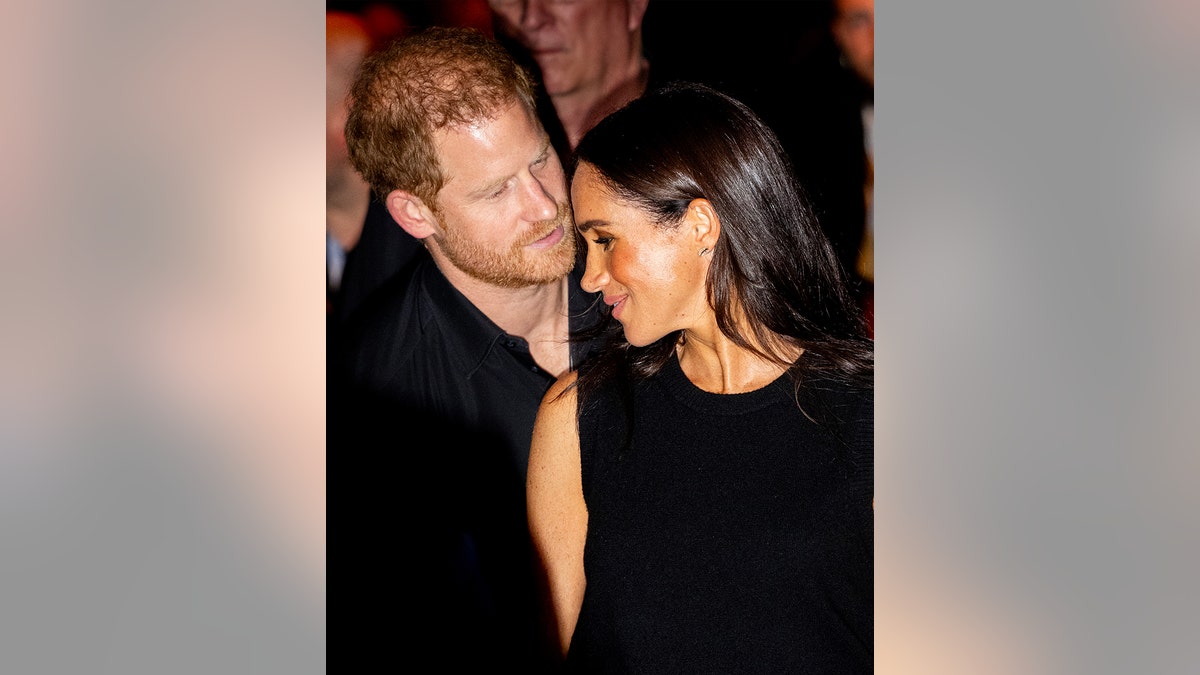 Meghan Markle and Prince Harry wearing matching black ensembles saring adoringly at each other