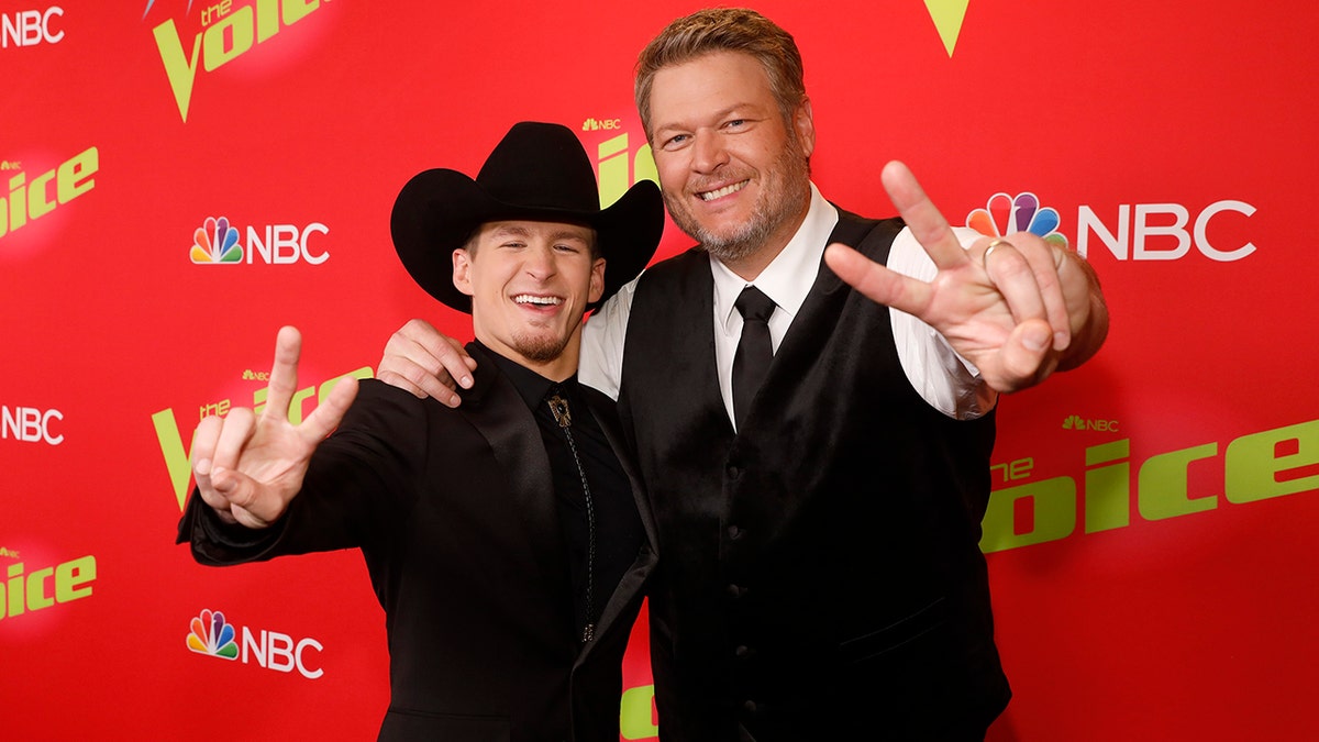 Bryce Leatherwood in a black cowboy hat poses with coach Blake Shelton in a black vest and tie and white shirt on "The Voice" carpet