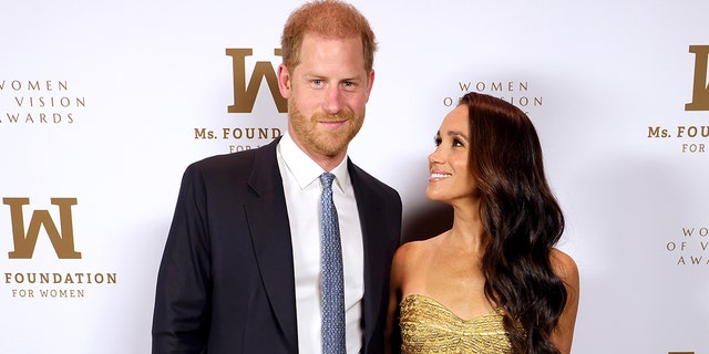 Meghan Markle looking up at Prince Harry during a step and repeat