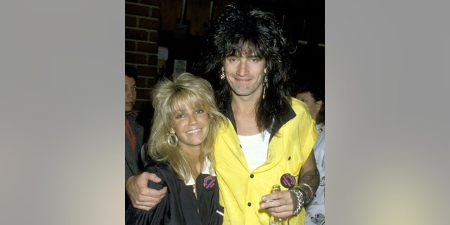 Heather Locklear smiles as Tommy Lee in a yellow shirt wraps his arm around her at the Calabasas Country Club