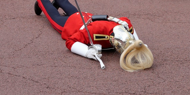 A member of the British military laying on the ground after fainting.
