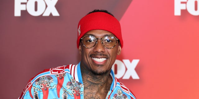 Nick Cannon smiles at the Fox Upfronts, in a red and blue shirt