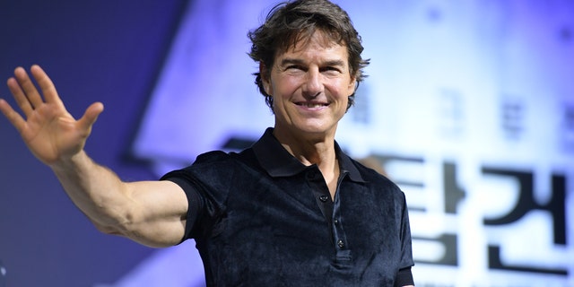 Tom Cruise waving in a short sleeve shirt