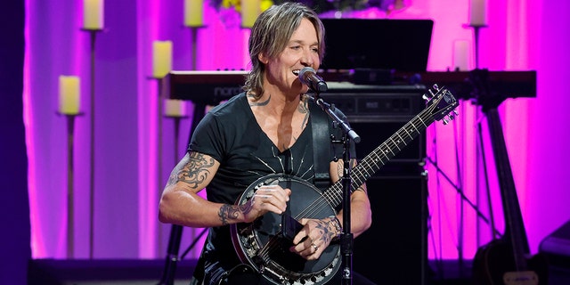 Keith Urban playing the banjo on stage