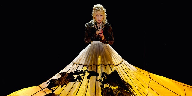 Dolly Parton performs her song "World on Fire" at the ACM awards for the first time, in a black top with a large yellow skirt that has a map of the world on it