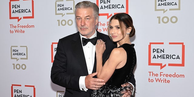 Alec Baldwin in a classic tuxedo holds onto wife Hilaria in a black outfit, while attending the PEN America Literary Gala
