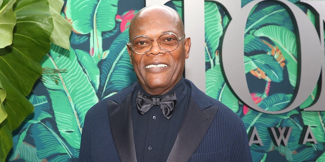 Samuel L Jackson smiles in a navy suit on the Tony Awards red carpet in New York
