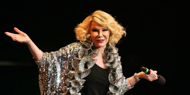 Joan Rivers shrugging on stage with a microphone