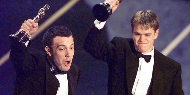 Ben Affleck, left, and Matt Damon hold up their Oscars after winning in the Original Screenplay Category during the 70th Academy Awards.