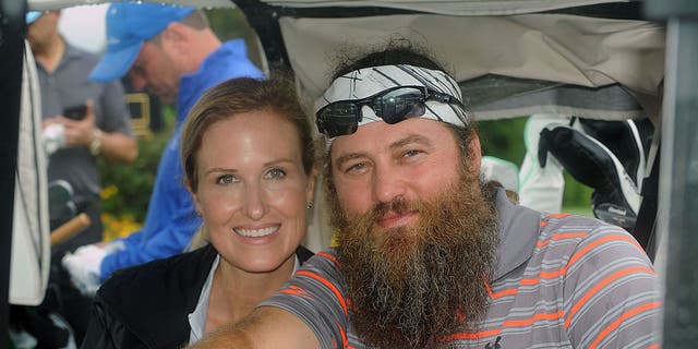 willie and korie robertson smiling in golf cart