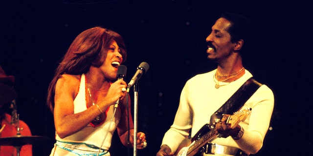 Tina Turner performs in a white dress alongside Ike Turner.