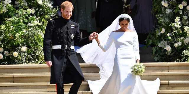 Prince Harry holds Meghan Markle's hand as they walk down the stairs at George's Chapel where they just got married at Windsor Castle