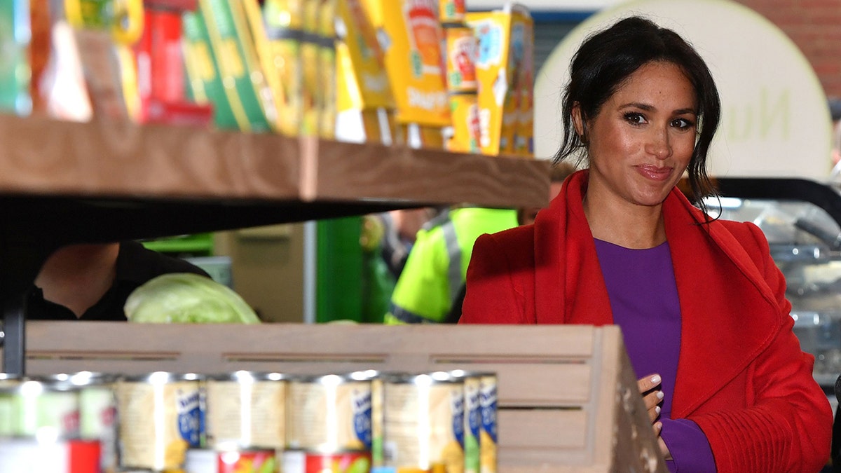 Meghan Markle looking at cans of food