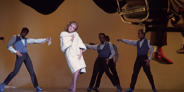 Ann-Margret wearing a white coat while performing on stage
