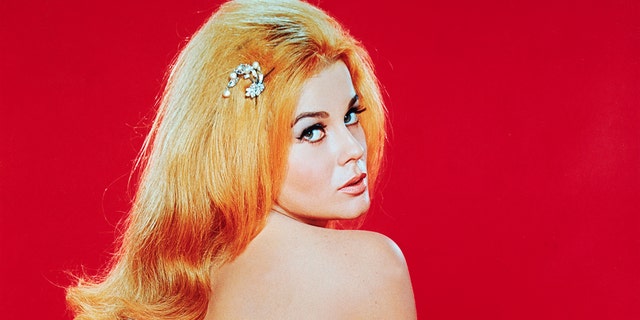 Ann-Margret wrapped in pink fur looking towards the camera