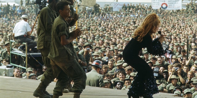 Troops dancing on stage with Ann-Margret who is singing in bell bottoms