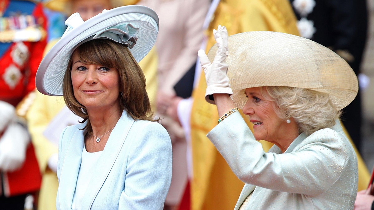Carole Middleton sitting next to Queen Camilla who is waving to a crowd