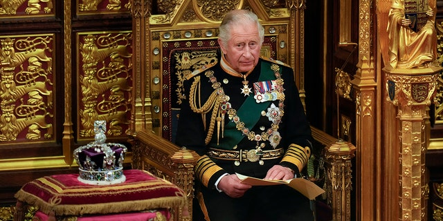 King Charles in royal regalia sitting on a throne next to a crown