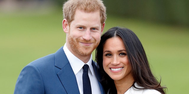 a close-up of Prince Harry in a blue suit and tie with meghan markle wearing a white coat
