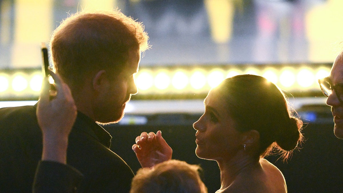 Prince Harry and Meghan Markle looking at each other in a crowd