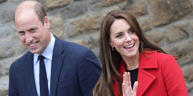 A close-up of Prince William in a blue suit and Kate Middleton wearing a red coat