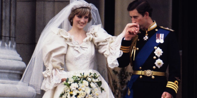 Princess Diana in a bridal gown having her hand kissed by her groom Prince Charles