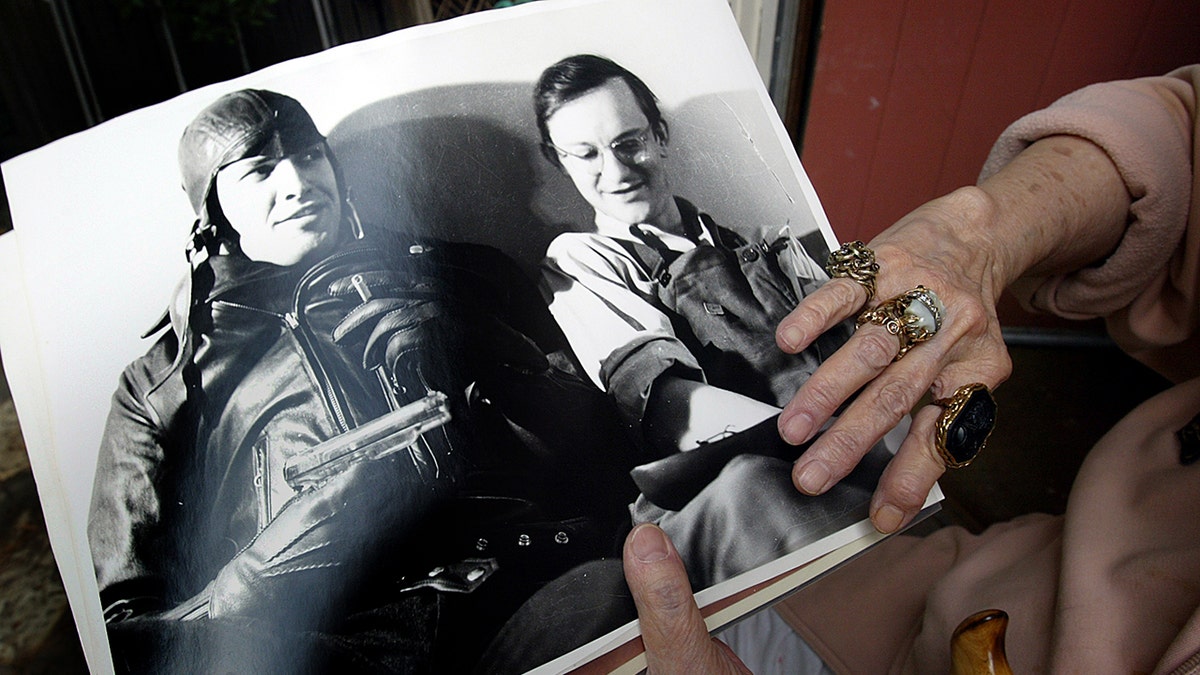 Wally Coxs widow holding a photo of Wally Cox sitting next to Marlon Brando