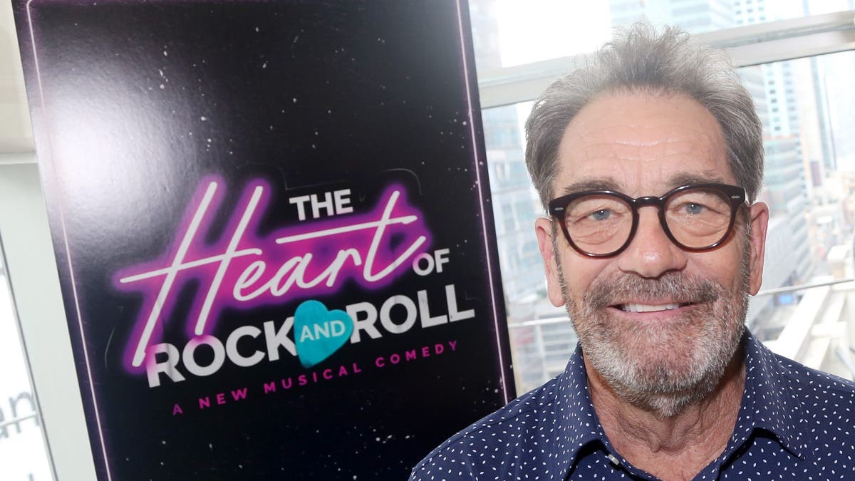 Huey Lewis standing in front of a sign for his musical