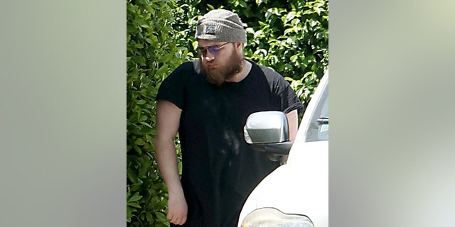 Angus T. Jones outside his home walking barefoot next to a car