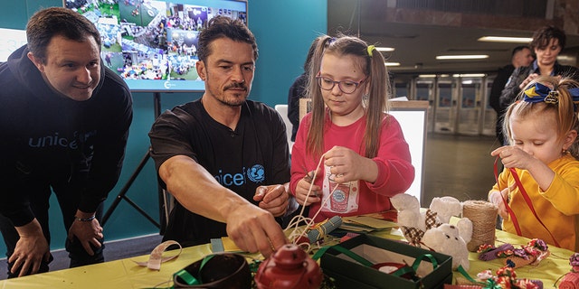 UNICEF Goodwill Ambassador Orlando Bloom makes a candle with 8-year-old Milana and her 3-year-old sister, Alisa, during a class in a UNICEF Spilno Child Spot at a metro station in Kyiv, Ukraine. 