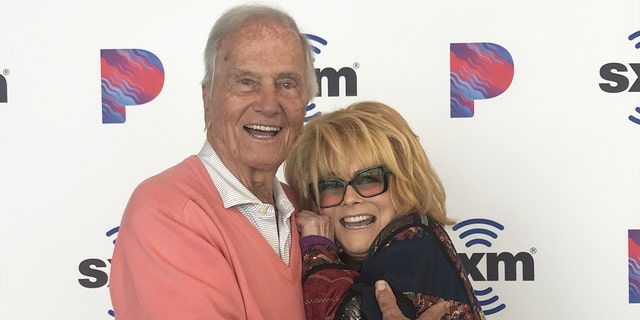 Pat Boone in a pink sweater hugging a smiling Ann-Margret in glasses