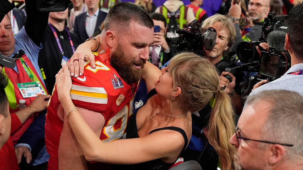 Taylor Swift looks lovingly up at Travis Kelce in his red Chiefs uniform after the Super Bowl