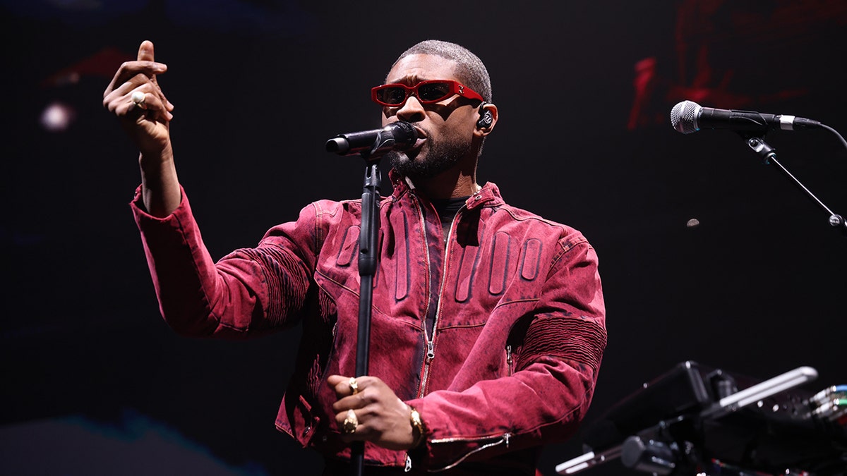 Usher performing onstage in sunglasses