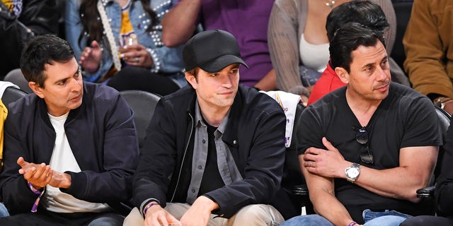 Robert Pattinson in a black baseball hat at Lakers game