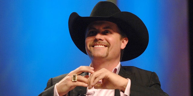 John Rich wears black cowboy hat and blazer on stage