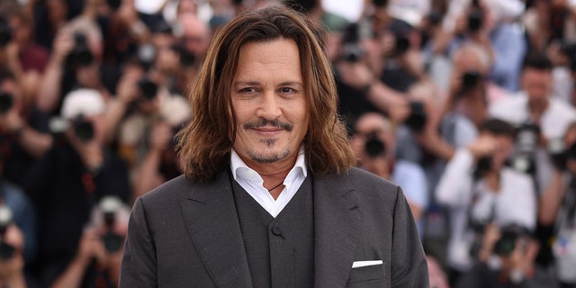 Johnny Depp walks Cannes Film Festival red carpet wearing grey suit with white shirt