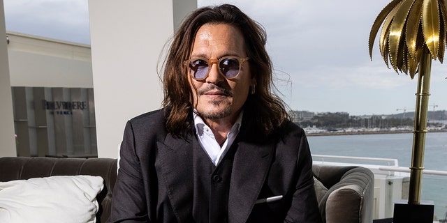 Johnny Depp wears black suit with shirt and glasses 