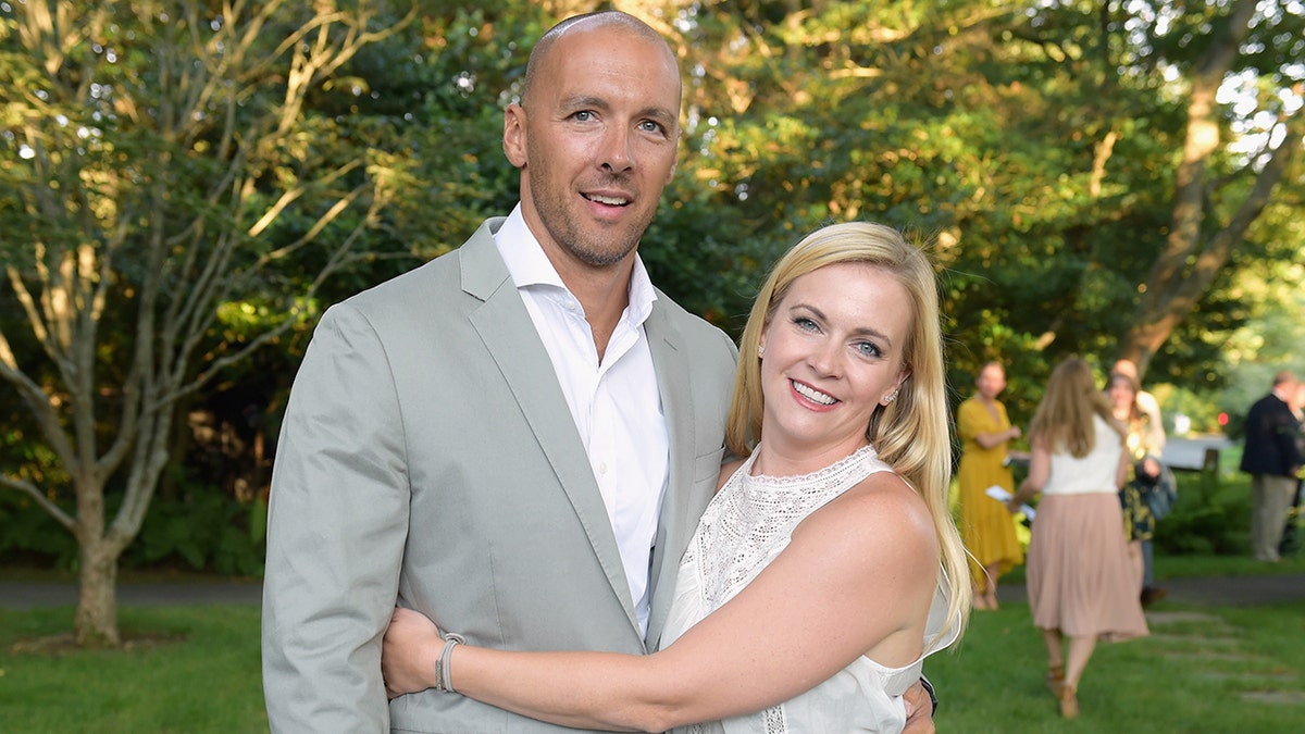 Melissa Joan Hart in a white outfit hugs husband Mark Wilkerson in a grey suit