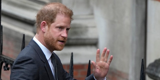 Prince Harry waves to onlookers as he arrives to court on Tuesday.